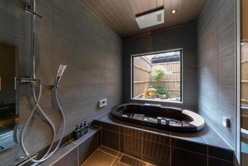 金泽Ainotsuji Machiya House的一间带浴缸和淋浴的浴室,并设有一个窗户