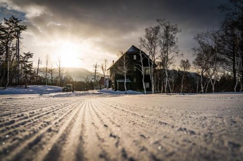 小谷村Cortina Apartment的雪中的房子,太阳在后面