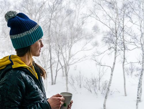 小谷村Cortina Apartment的雪中喝咖啡的妇女