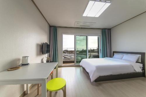 西归浦市济州岛膳食度假屋的一间卧室配有一张床、一张书桌和一个窗户。