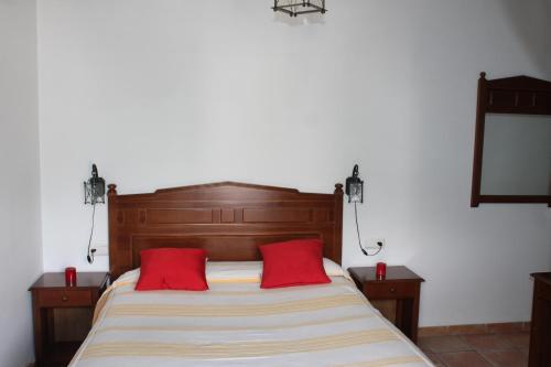 卡皮雷拉Apartamentos Rurales Rosendo: "La Pimienta"的一间卧室配有一张带两个红色枕头的床