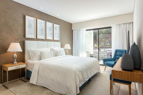 阿尔布费拉Pine Cliffs Gardens的卧室配有白色的床和蓝色椅子