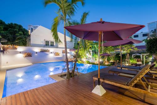 华欣Anchan Hotel & Spa的一个带遮阳伞和躺椅的游泳池以及一个游泳池