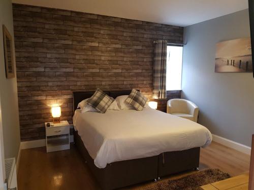 St Margaret's HopeThorshaven Apartment, Orkney的一间卧室设有一张大床和砖墙