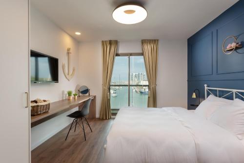 荷兹利亚BHerzliya Marina Lagoon Apartment的一间卧室配有一张床和一张带窗户的书桌