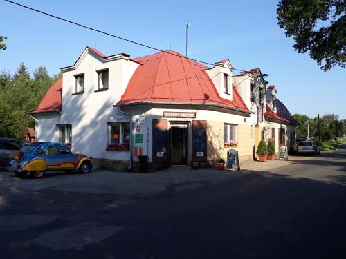JanovicePension u Adršpachu - Dana Tyšerová的停在一座红色屋顶建筑前面的汽车