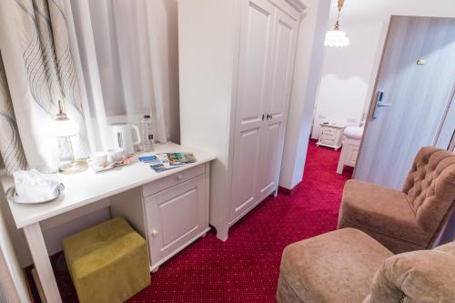 克拉约瓦大卫酒店的客房配有书桌和椅子,铺有红地毯。