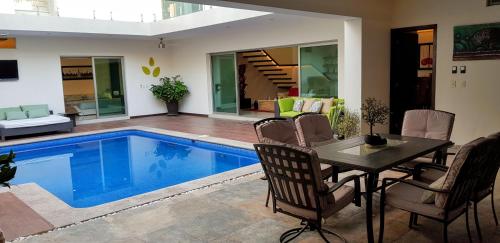 科利马Suites Lagunas的客厅设有游泳池、桌子和椅子