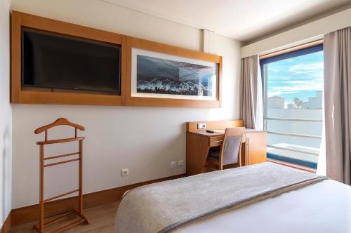蓬塔德尔加达蓬塔德尔加达康福特茵酒店的酒店客房配有一张床、一张书桌和一台电视。