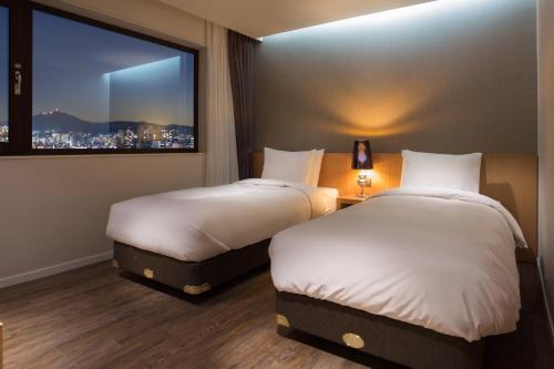 首尔首尔情侣酒店的配有窗户的酒店客房内的两张床