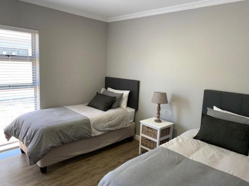 兰格班679 Morsvalla Way Langebaan Golf Estate的一间卧室设有两张床、一盏灯和一扇窗户。