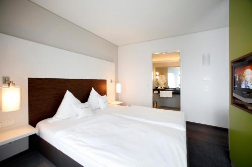卡门SportHotel Kaiserau的卧室配有白色的床和电视。