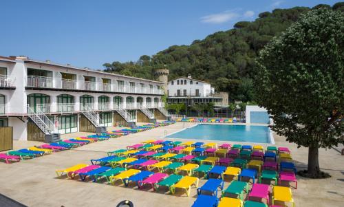 滨海托萨Medplaya Aparthotel Sant Eloi的一座游泳池旁,配有五颜六色的遮阳伞和椅子