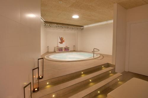 潘普洛纳Hotel Pompaelo Plaza del Ayuntamiento & Spa的一个带灯光的客房内大型按摩浴缸