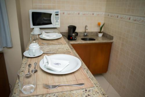 马卡埃Gloria Garden Suites的厨房柜台配有盘子和餐具以及微波炉