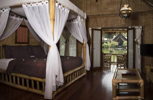 加鲁特甘榜萨姆皮乌度假村和Spa酒店的卧室配有带白色窗帘的天蓬床
