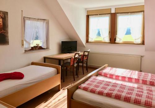 阿尔斯费尔德Gasthaus Zur Hardtmühle的客房设有两张床、一张桌子和一张书桌。