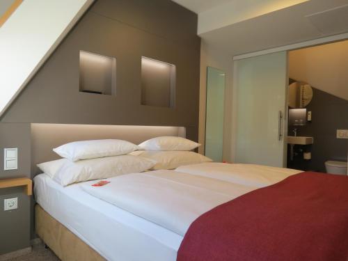 乌尔姆纽托尔酒店的卧室配有一张带白色床单和枕头的大床。