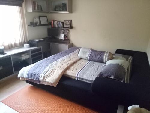 万隆Homestay Syariah Cileunyi, Bandung Timur的一间卧室配有一张带书桌的床和窗户。