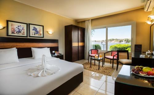 阿斯旺Obelisk Nile Hotel Aswan的酒店客房设有一张床和一张带果盘的桌子。