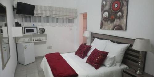 SasolburgAzrielle Guesthouse的一间卧室配有一张带红色枕头的大床