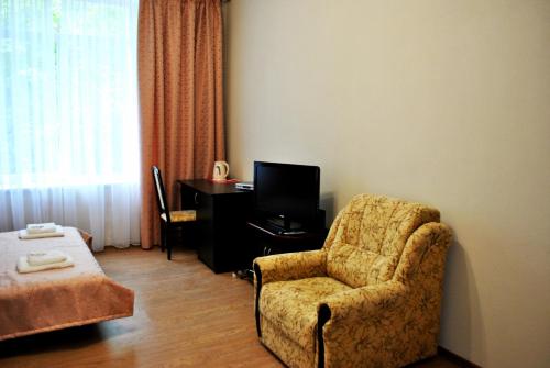 哈尔科夫艾格雅酒店的一间带椅子、书桌和电视的房间