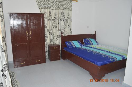 班珠尔Sukuta Nema Guest House的一间卧室配有一张床和一个木制橱柜