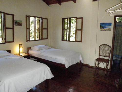 特纳Jungle Lodge El Jardin Aleman的一间卧室设有两张床、一把椅子和窗户。