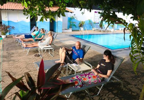 尼甘布黄玉海滩酒店的一群人坐在游泳池旁的草坪椅上