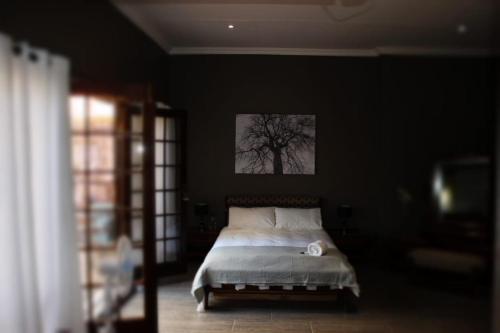 莫迪默勒Jean-Alno的卧室配有一张床铺,墙上挂着一棵树
