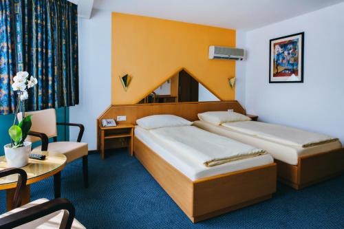 莱茵河畔威尔Hotel Central的酒店客房设有两张床和一张桌子。