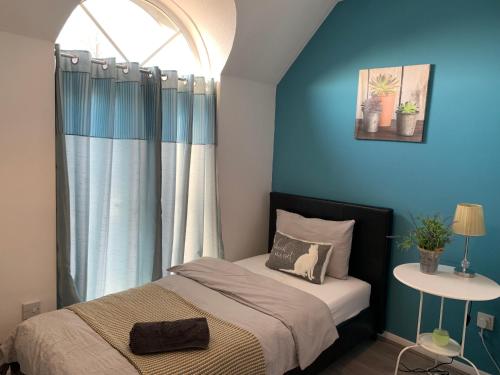 凯特林Eskdaill Place Apartment的一间卧室配有一张蓝色墙壁的床和一扇窗户