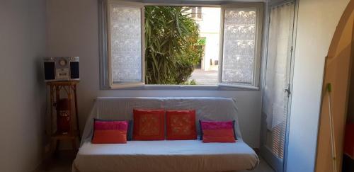 芒通location saisonnière的窗户下配有4个枕头的白色沙发