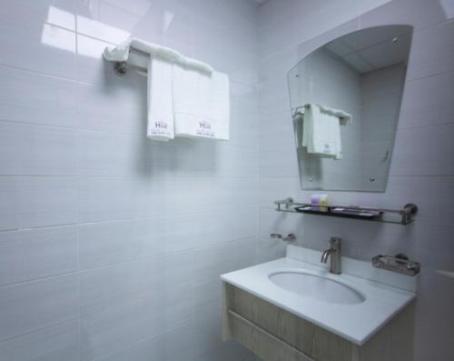 马斯喀特Home Station Hotel的白色的浴室设有水槽和镜子