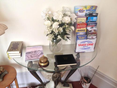 滨海绍森德Malvern Lodge Guest House- Close to Beach, Train Station & Southend Airport的花瓶和书的玻璃桌