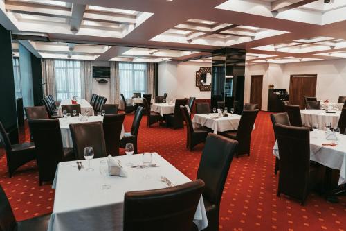 巴克乌EMD酒店的一间设有白色桌椅的用餐室
