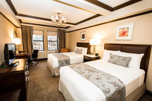 纽约The Belvedere Hotel的酒店客房设有两张床、一张桌子和一台电视。