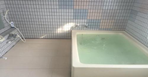 妙高Myoko - Hotel / Vacation STAY 17055的浴室铺有白色瓷砖,配有浴缸。