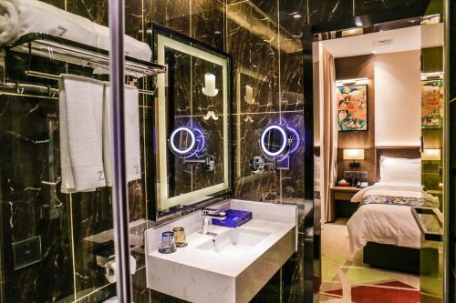 广州潮漫酒店(广州琶洲会展中心赤岗地铁站店)的一间带水槽和镜子的浴室以及一张床