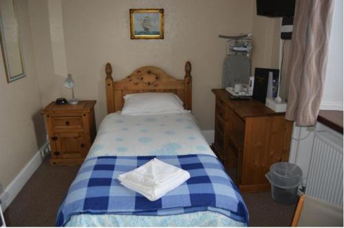 威克Queens hotel的卧室配有蓝色和白色的床和木制家具