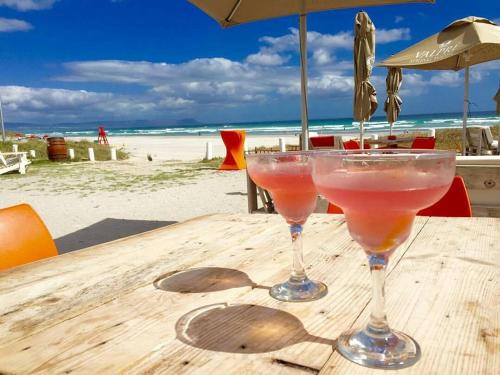 赫曼努斯Dawn's Place的两只马提尼玻璃杯坐在海滩木桌旁