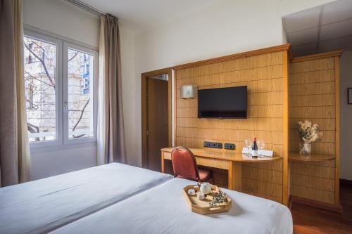 马德里Negresco Gran Via的酒店客房配有一张床、一张书桌和一台电视。