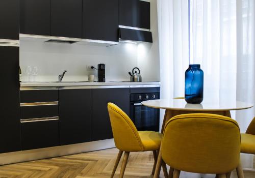 米兰Serendipity Apartments - Duomo的厨房配有带黄色椅子和蓝色花瓶的桌子