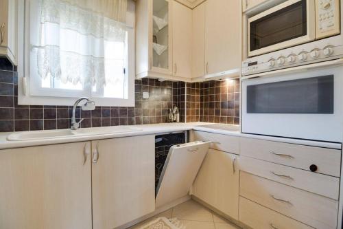 弗洛伊塔Villa Natali的厨房配有白色橱柜、水槽和微波炉