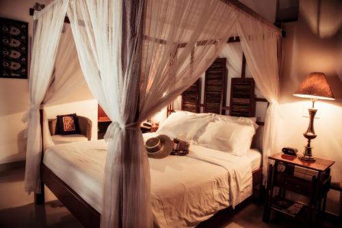 圣玛尔塔卡萨伊莎贝拉，卡利酒店的卧室配有带白色窗帘的天蓬床