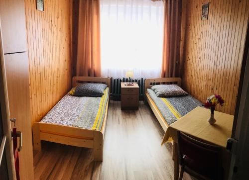 乌伊索维Pokoje Gościnne的客房设有两张床、一张桌子和一扇窗户。