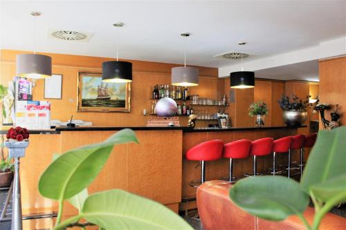 杜塞尔多夫Rugs Hotel Düsseldorf的餐厅内带红色凳子的酒吧