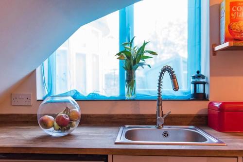 马盖特Garden Oasis的厨房水槽,窗户旁有一碗水果