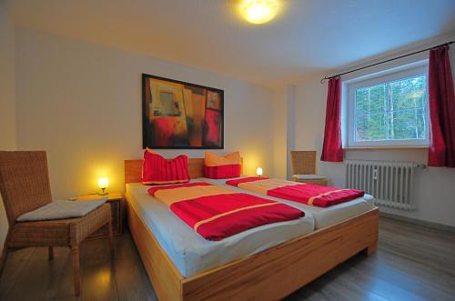 欣特察尔滕Ferienhaus Hinterzarten的一间卧室配有一张带红色枕头的大床