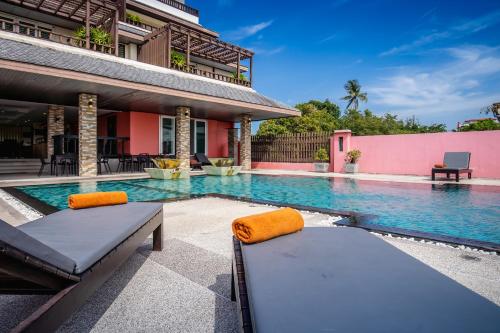 拉威海滩Ratana Hotel Chalong的房屋前设有2张床的游泳池